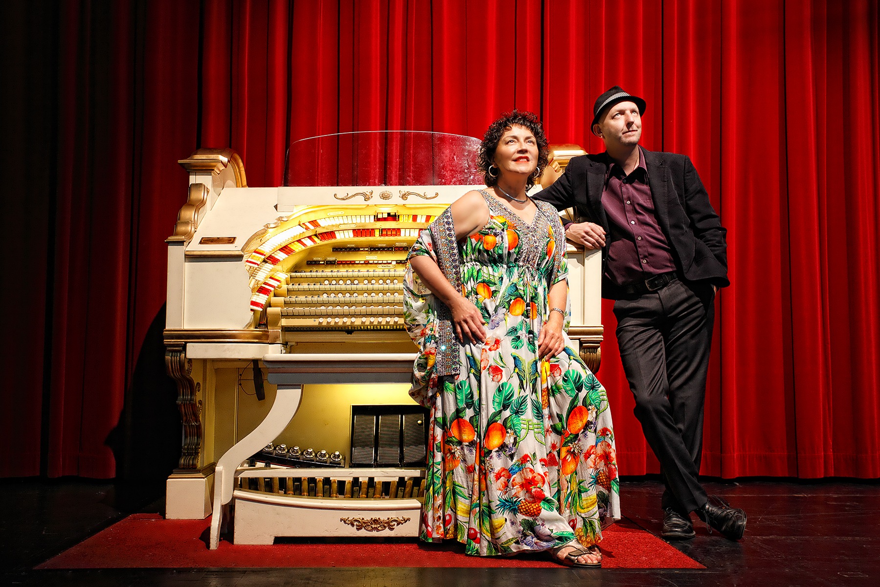 Ruby Page and Scott Harrison with the theatre Wurlitzer against red curtains